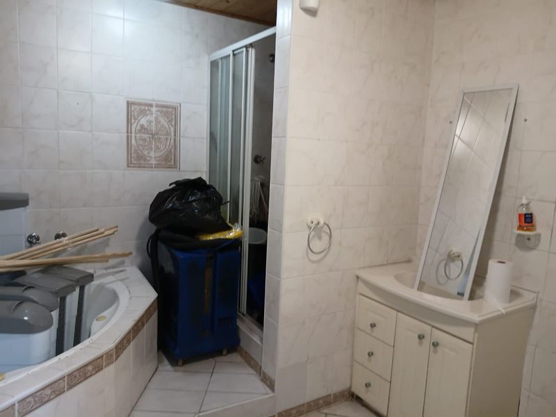 A dated bathroom featuring a corner bathtub, a separate shower enclosure, and a vanity cabinet with an integrated sink, finished with tiled surfaces.