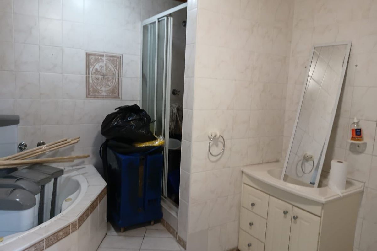 A dated bathroom featuring a corner bathtub, a separate shower enclosure, and a vanity cabinet with an integrated sink, finished with tiled surfaces.