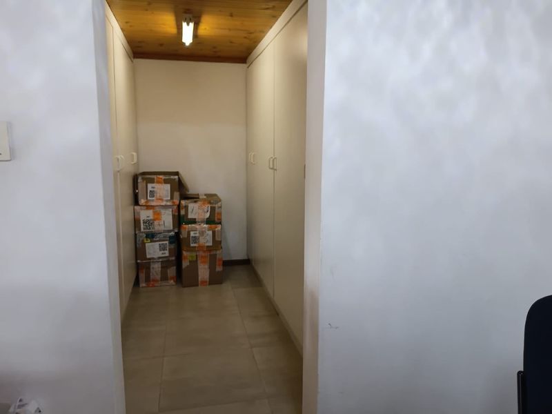 A functional utility space or storage area featuring built-in cabinetry, tiled flooring, and a timber-paneled ceiling.