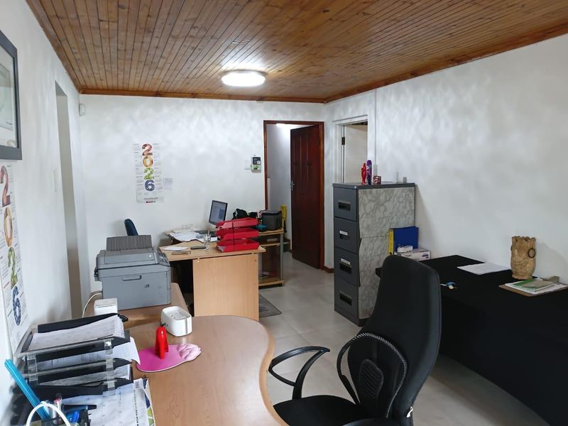 A functional office space featuring a timber tongue and groove ceiling, tiled flooring, and neutral wall finishes.