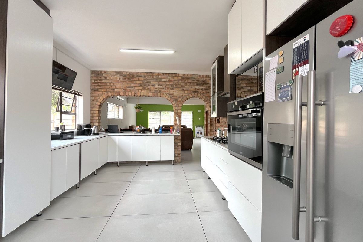 Modern kitchen featuring white cabinetry, tiled floors, and a distinctive brick archway leading to the adjacent living area.
