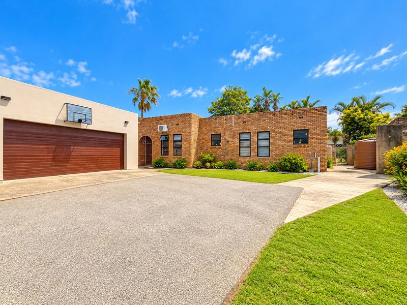 Front exterior view of a well-maintained brick house featuring a spacious concrete driveway, double garage, and landscaped garden area.
