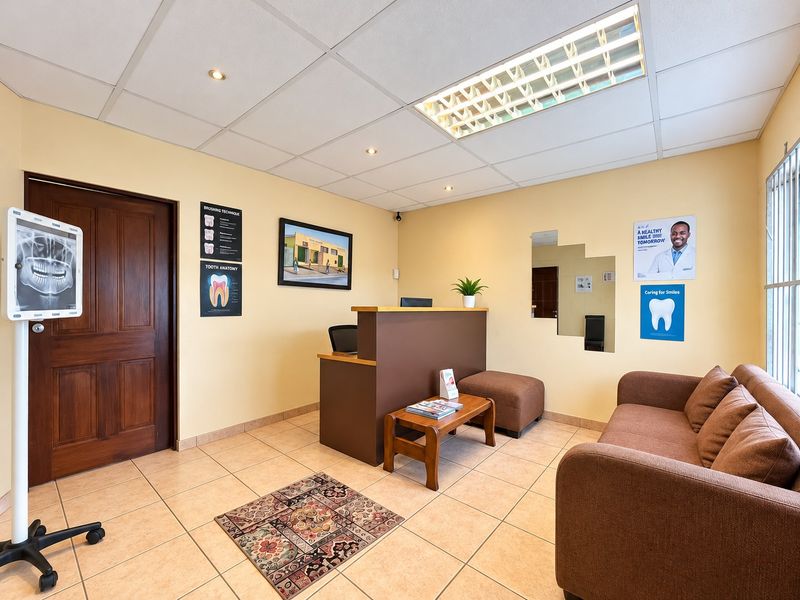 A professional reception or waiting area featuring tiled flooring, a suspended ceiling with integrated lighting, and a built-in reception desk.