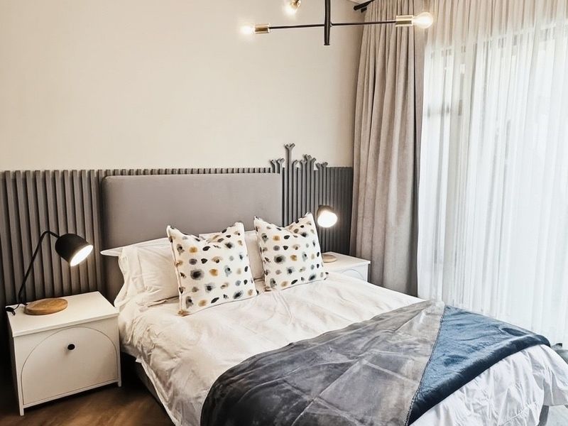 A modern, well-appointed bedroom featuring elegant vertical slat wall paneling, herringbone timber flooring, and sophisticated lighting fixtures.