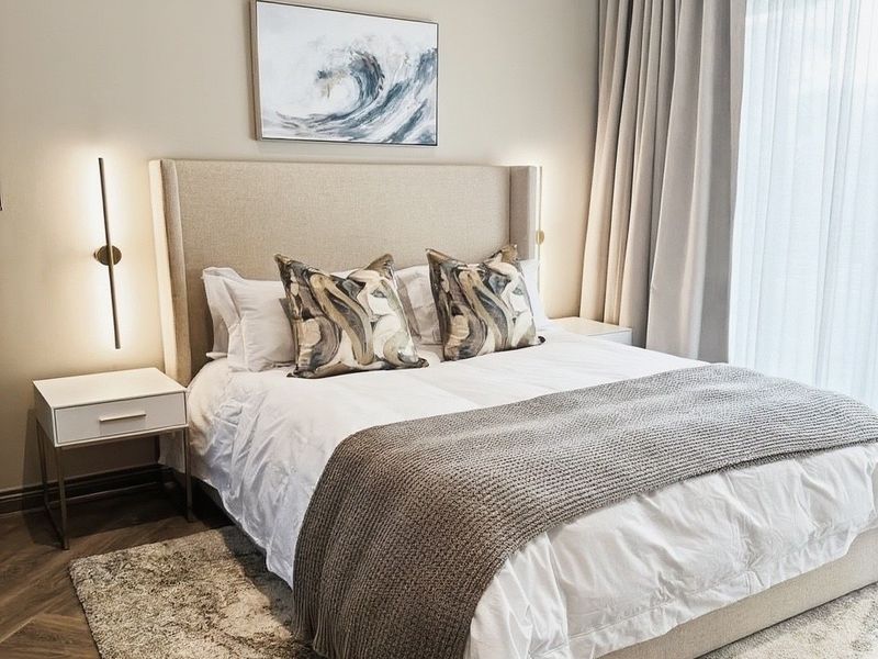 A well-appointed bedroom featuring elegant herringbone timber flooring, floor-to-ceiling curtains, and modern recessed wall lighting, creating a sophisticated and comfortable living space.