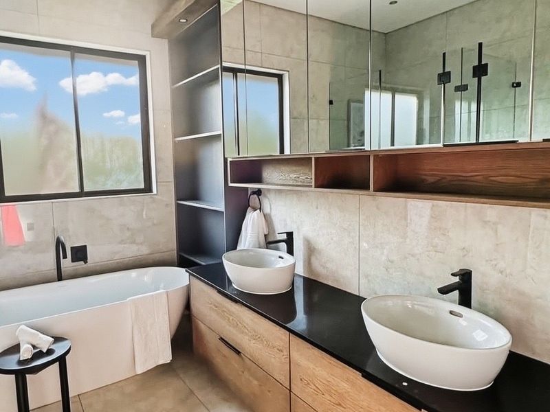 Modern bathroom featuring a double vanity with vessel sinks, a sleek freestanding bathtub, and extensive built-in cabinetry with integrated mirrored storage.