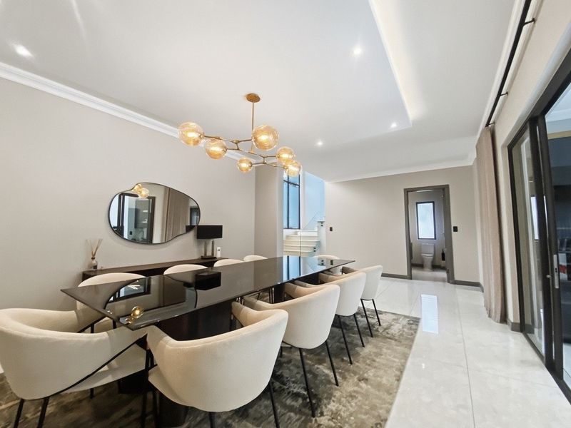 Elegant dining room featuring polished porcelain flooring, a modern recessed ceiling with cove lighting, and seamless access to the outdoor area via sliding glass doors.