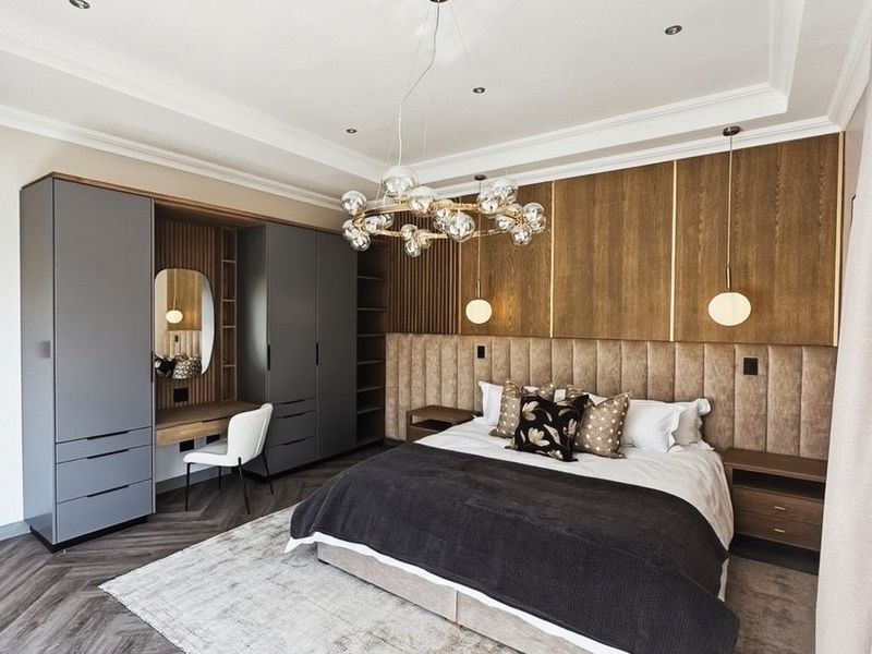 Luxurious bedroom featuring custom built-in wardrobes, integrated vanity, upholstered headboard, and elegant herringbone flooring with sophisticated recessed lighting.