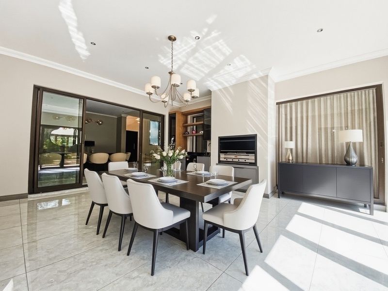 Elegant dining room featuring large format floor tiles, recessed lighting, crown molding, and a built-in fireplace, with seamless access to the outdoor patio area.