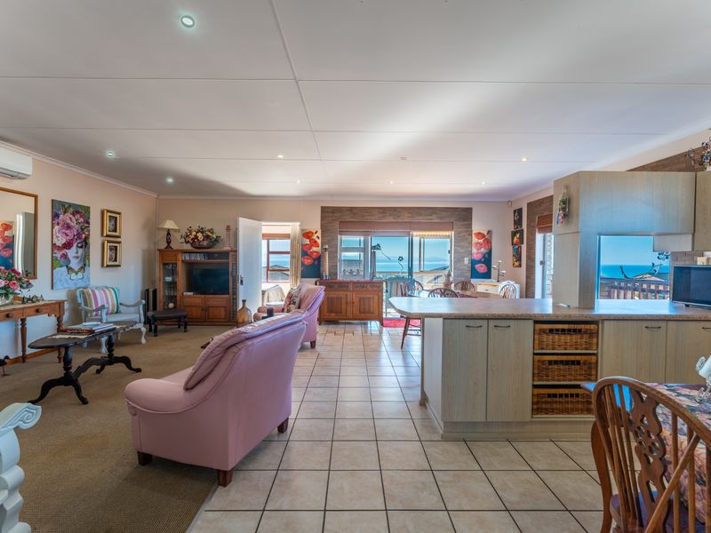 Spacious open-plan living and kitchen area featuring tiled and carpeted flooring, built-in cabinetry, and sliding glass doors with ocean views.