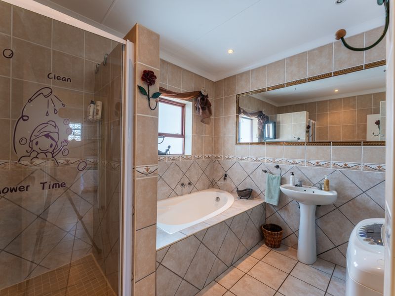 A functional bathroom featuring a tiled shower enclosure, a built-in bathtub, and a pedestal basin with neutral wall and floor tiling.