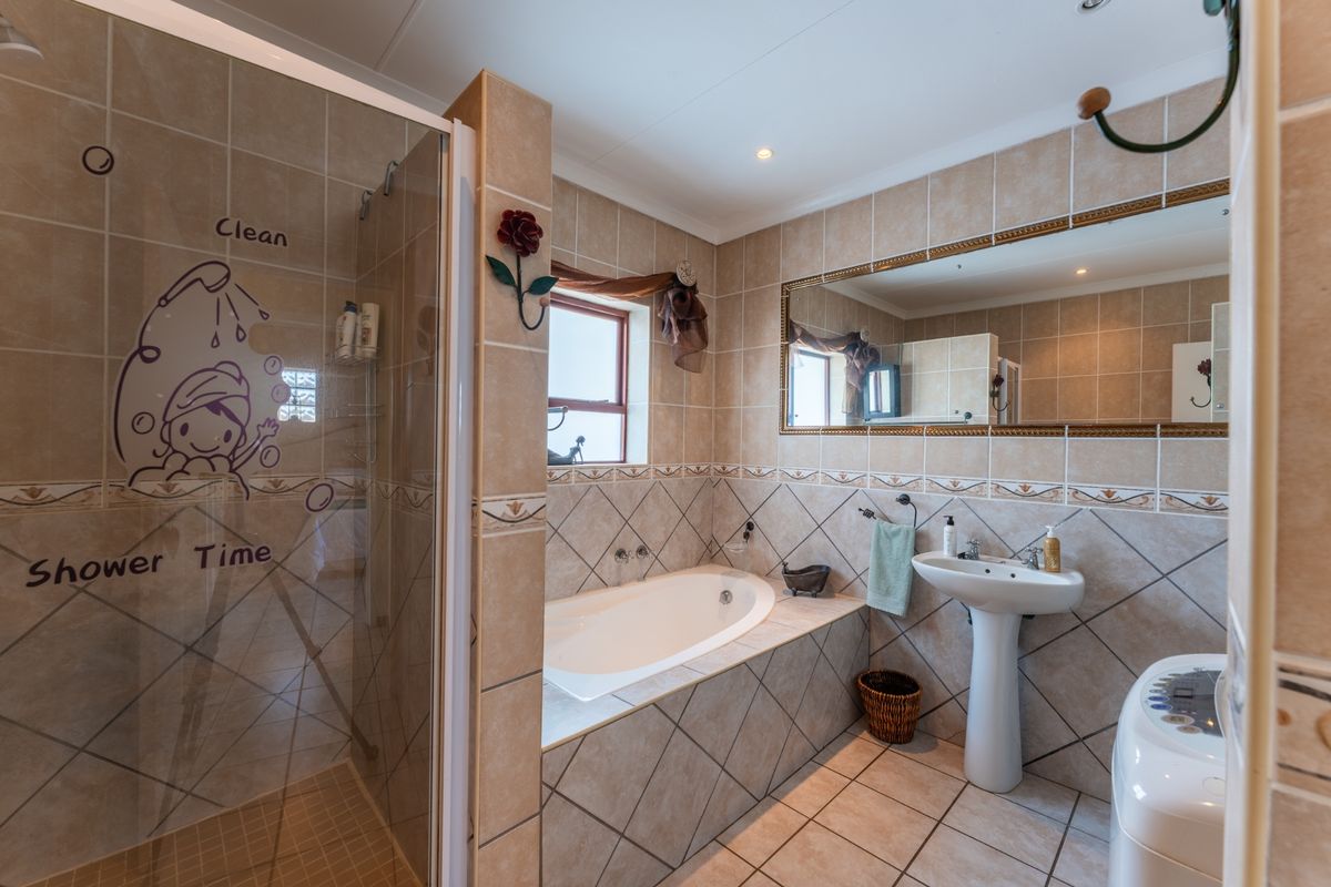 A functional bathroom featuring a tiled shower enclosure, a built-in bathtub, and a pedestal basin with neutral wall and floor tiling.