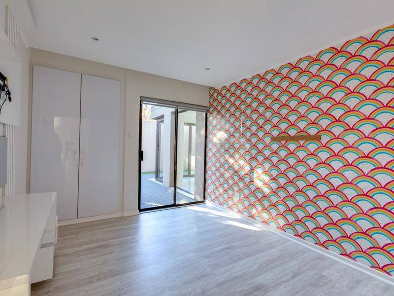 Bright bedroom featuring light laminate flooring, a built-in wardrobe, and a sliding glass door providing access to the outdoor area.