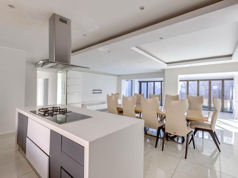 Spacious open-plan kitchen and dining area featuring a central island with gas hob, modern cabinetry, tiled floors, and large sliding doors leading outdoors.