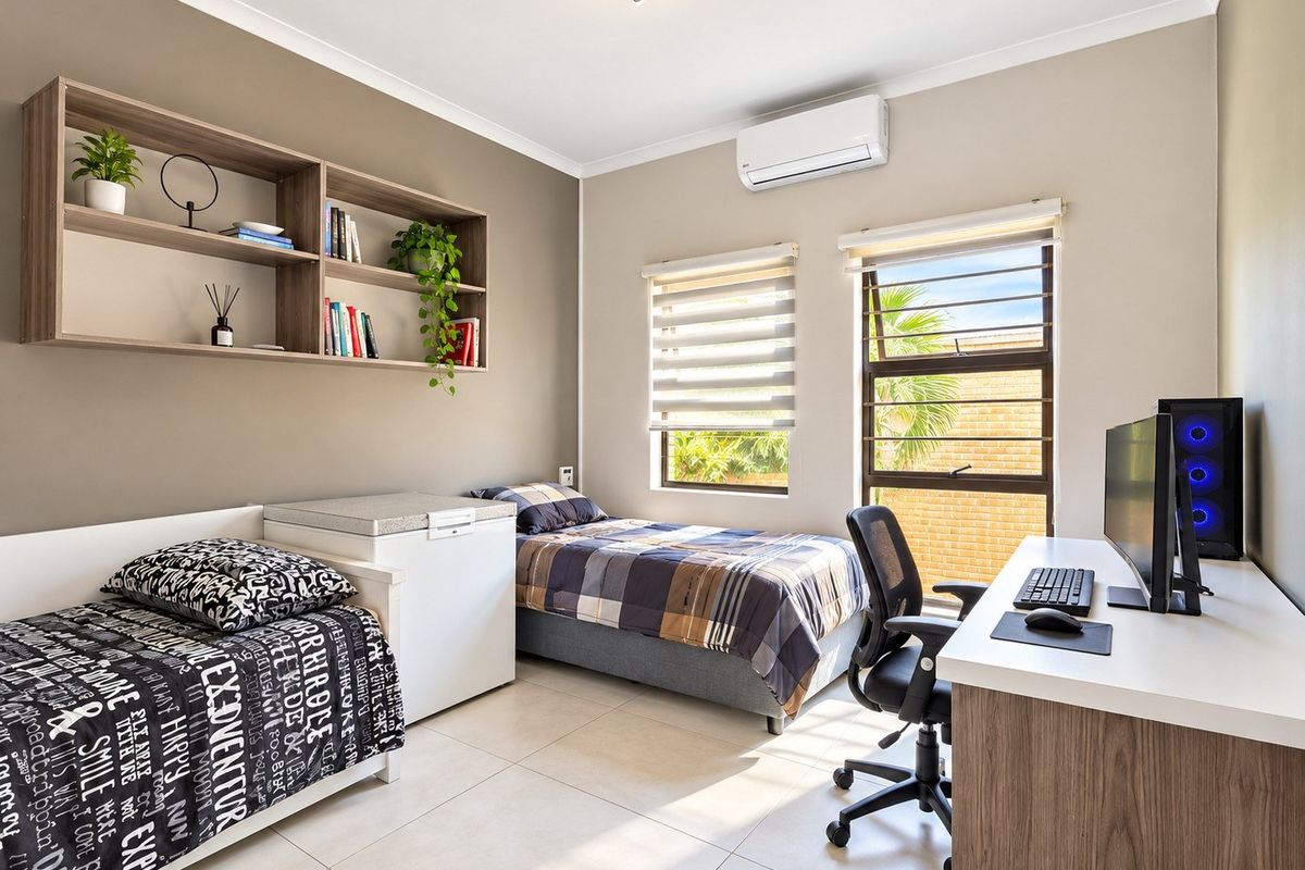 A well-maintained bedroom featuring tiled flooring, built-in shelving, and a split-system air conditioner, offering a functional and comfortable living space.