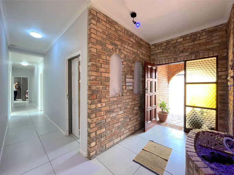 Welcoming entrance hall featuring an exposed brick feature wall with arched niches, tiled flooring, and a solid timber front door with textured glass.