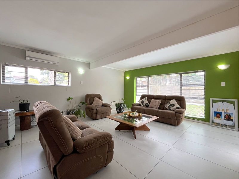 Spacious living room featuring large windows, tiled flooring, and a wall-mounted air conditioning unit, offering a bright and comfortable living space.