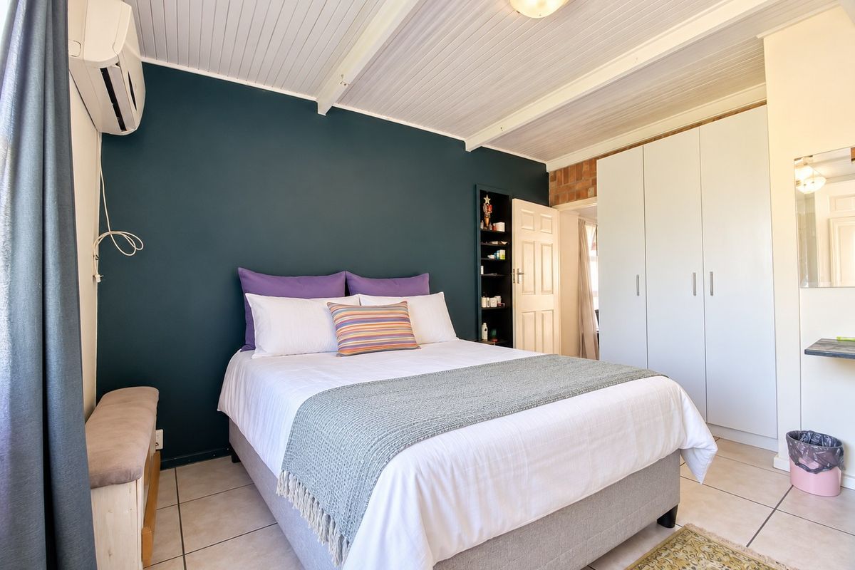 A well-maintained bedroom featuring tiled flooring, built-in cupboards, a tongue and groove ceiling, and an integrated air conditioning unit.