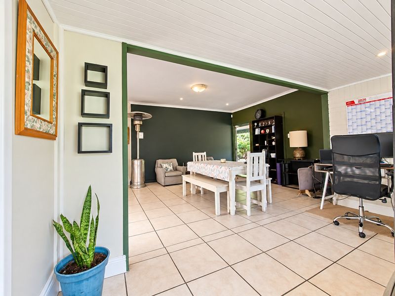 An open-plan living and dining area featuring tiled flooring, a tongue and groove ceiling, and dark green accent walls.