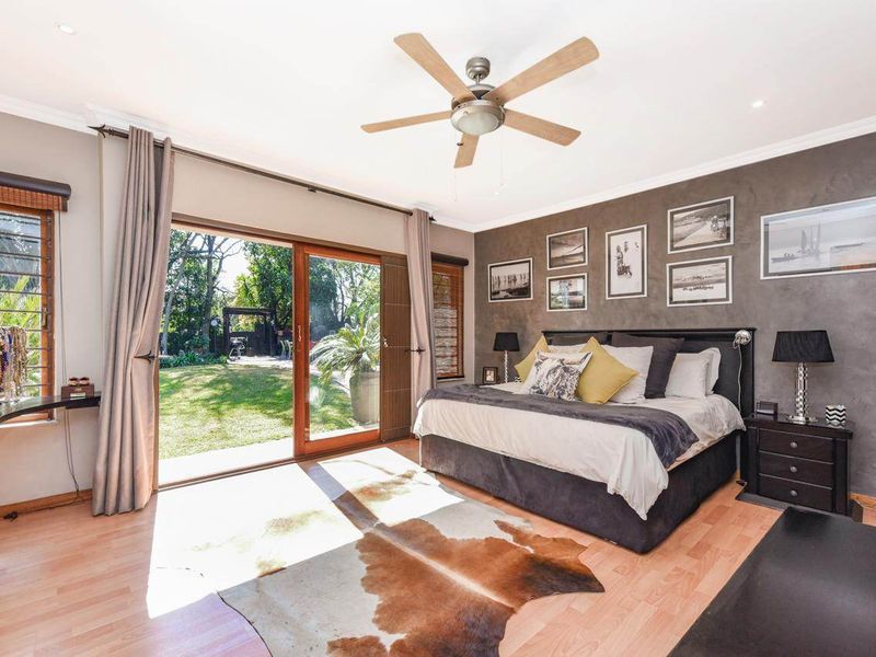 Spacious bedroom featuring a textured accent wall, ceiling fan, and large sliding glass doors providing direct access to the rear garden.