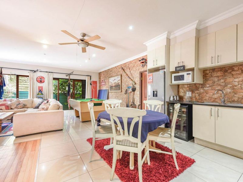 Spacious open-plan living and kitchen area featuring a stone veneer accent wall, tiled flooring, and direct access to the outdoor space via sliding doors.