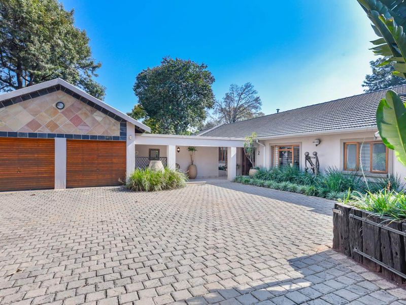 A well-maintained front exterior featuring a paved driveway, double garage with timber doors, and a covered entrance area.