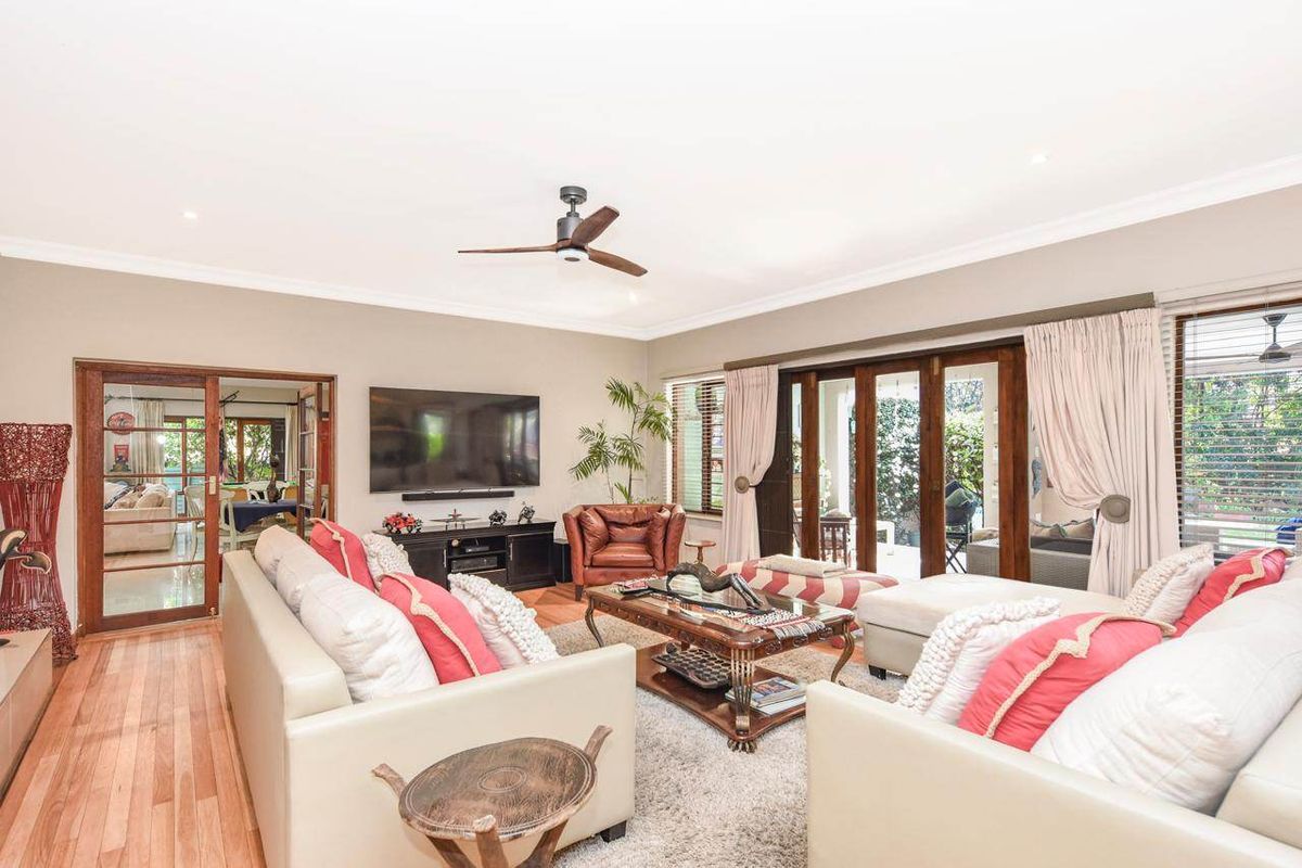 Spacious living room featuring hardwood flooring, recessed lighting, a ceiling fan, and large sliding glass doors providing access to the outdoor area.