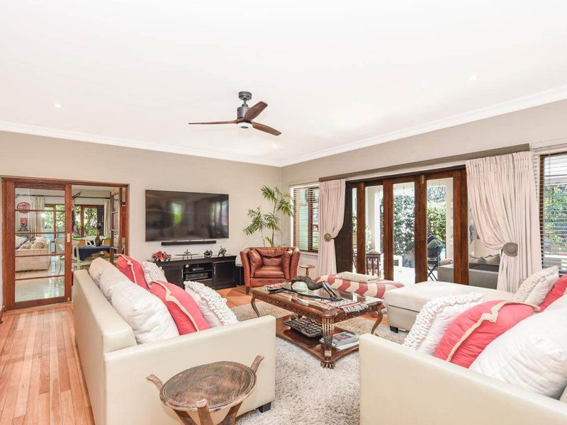 Spacious living room featuring hardwood flooring, recessed lighting, a ceiling fan, and large sliding glass doors providing access to the outdoor area.