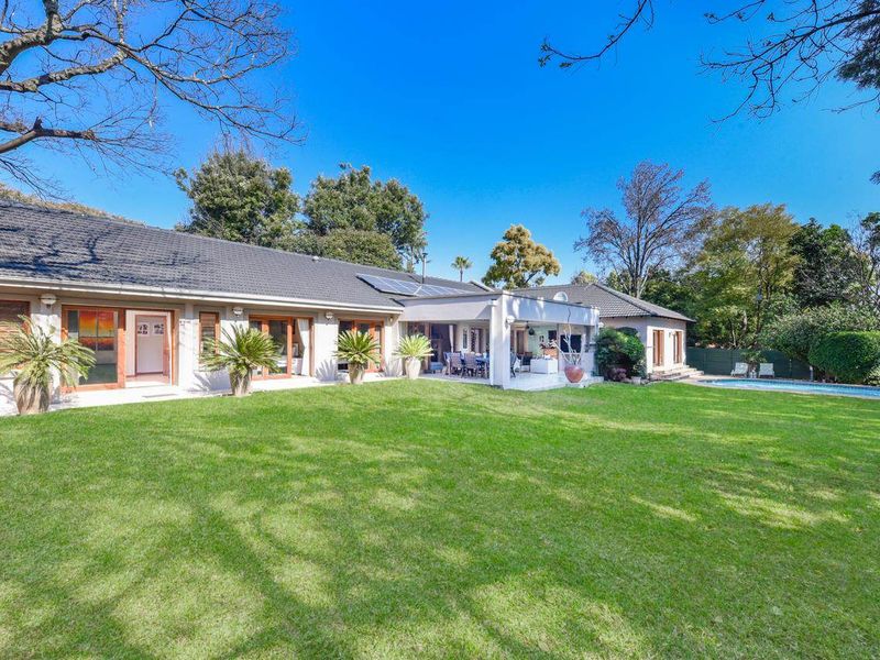 Spacious rear garden featuring a well-maintained lawn, a covered patio area, and a swimming pool, providing an ideal space for outdoor relaxation and entertainment.
