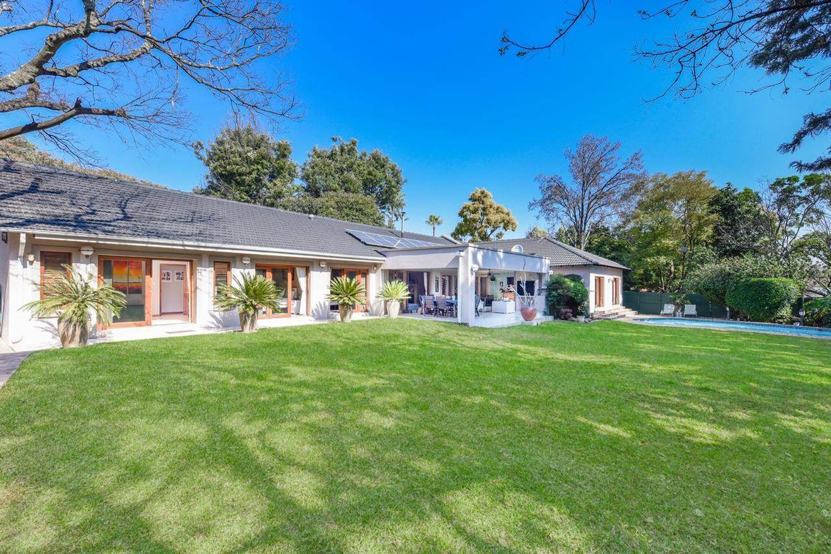 Spacious rear garden featuring a well-maintained lawn, a covered patio area, and a swimming pool, providing an ideal space for outdoor relaxation and entertainment.