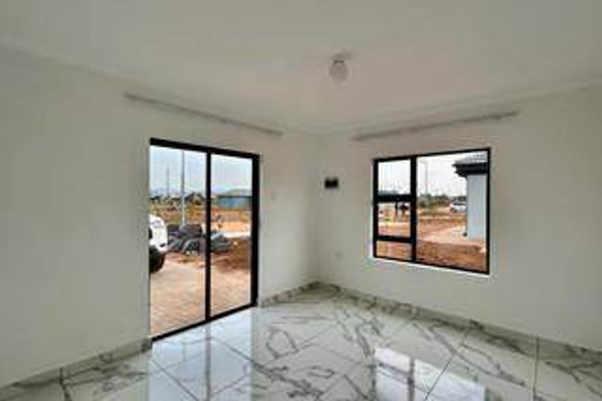 A bright, empty living area featuring modern marble-look floor tiles, aluminium window frames, and a sliding door leading to the exterior.