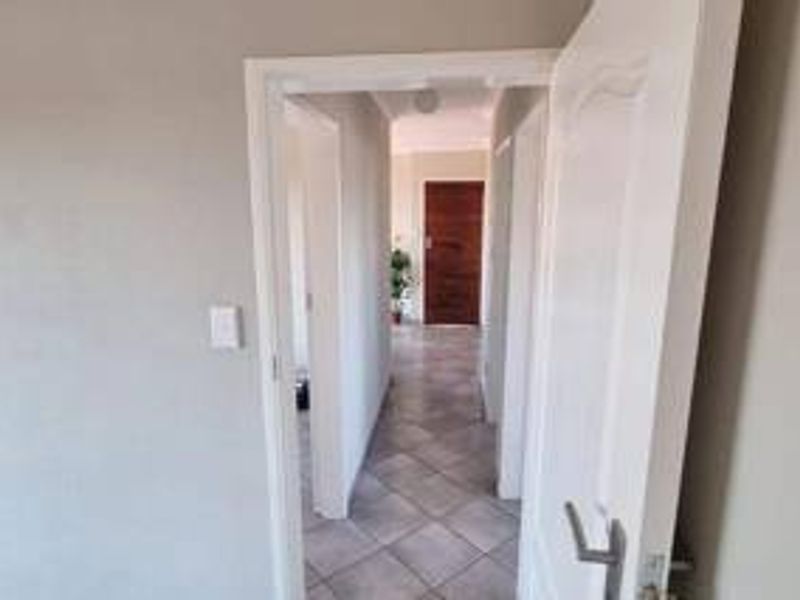A neutral-toned hallway featuring tiled flooring and connecting internal doors, providing access to various rooms within the home.