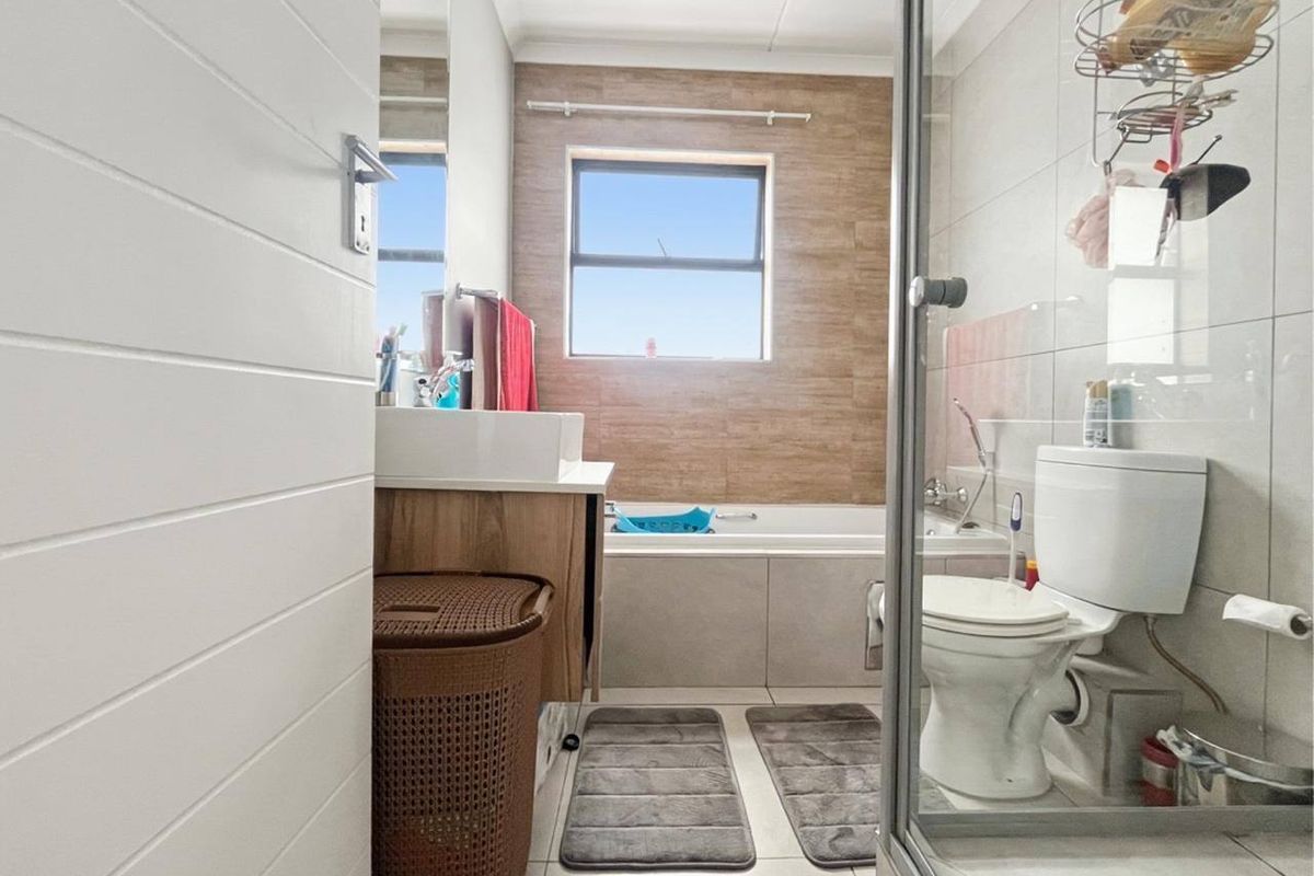 A functional bathroom featuring a bathtub, separate shower enclosure, vanity basin, and toilet with neutral tiled finishes.