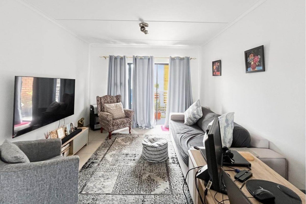 A comfortable living room featuring tiled flooring and a sliding glass door that provides access to an outdoor balcony area.