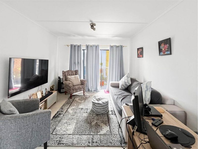 A comfortable living room featuring tiled flooring and a sliding glass door that provides access to an outdoor balcony area.