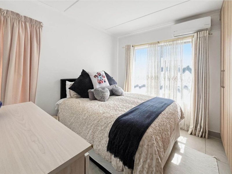 A well-lit bedroom featuring tiled flooring, a built-in wardrobe, and a wall-mounted split-system air conditioner.