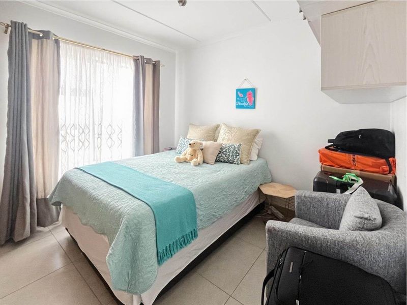 A functional bedroom featuring tiled flooring and built-in cabinetry, with natural light provided by a large window.