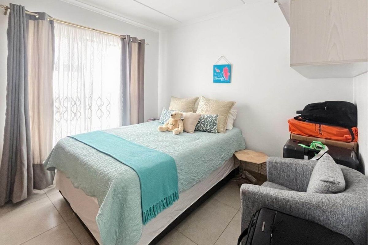 A functional bedroom featuring tiled flooring and built-in cabinetry, with natural light provided by a large window.