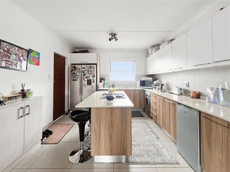 Modern kitchen featuring a central island with a gas hob, ample built-in cabinetry, stone countertops, and integrated laundry appliances.