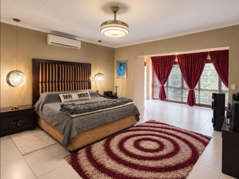 Spacious bedroom featuring tiled flooring, a split-system air conditioner, ceiling fan, and large windows allowing for ample natural light.