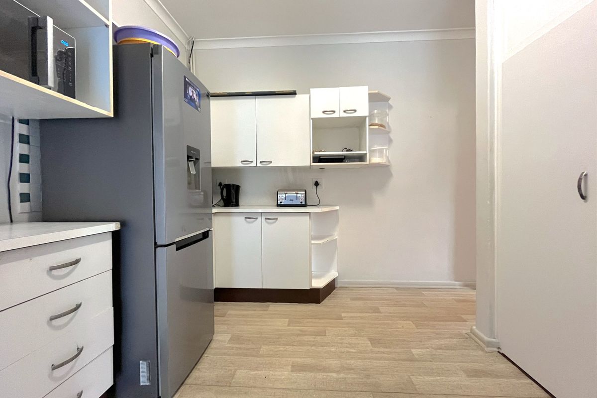 A functional kitchen featuring white built-in cabinetry, light wood-look laminate flooring, and a clean, neutral aesthetic.