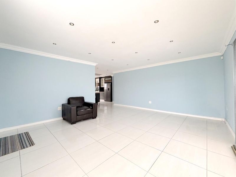 Spacious open-plan living area featuring neutral light blue walls, polished tiled flooring, and recessed downlighting throughout.