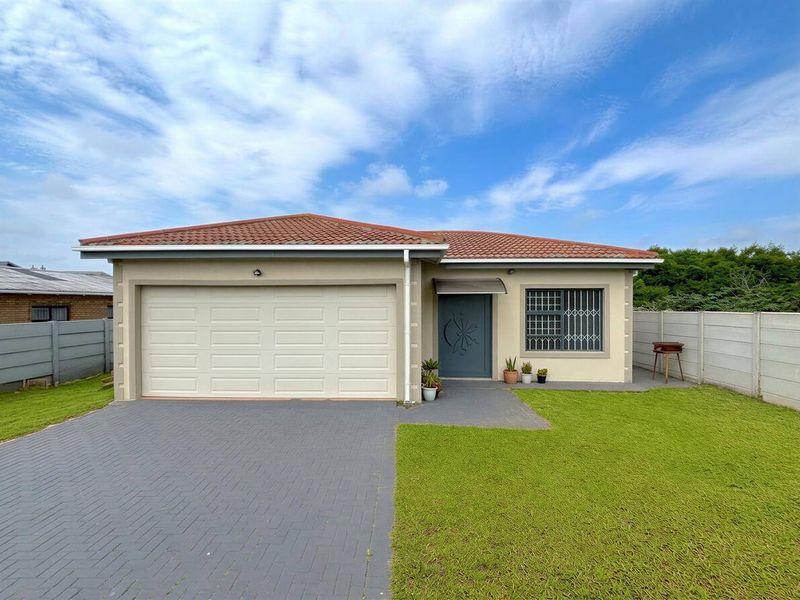 Front elevation of a single-story house featuring a paved driveway, double garage, and a well-maintained lawn with secure boundary walls.