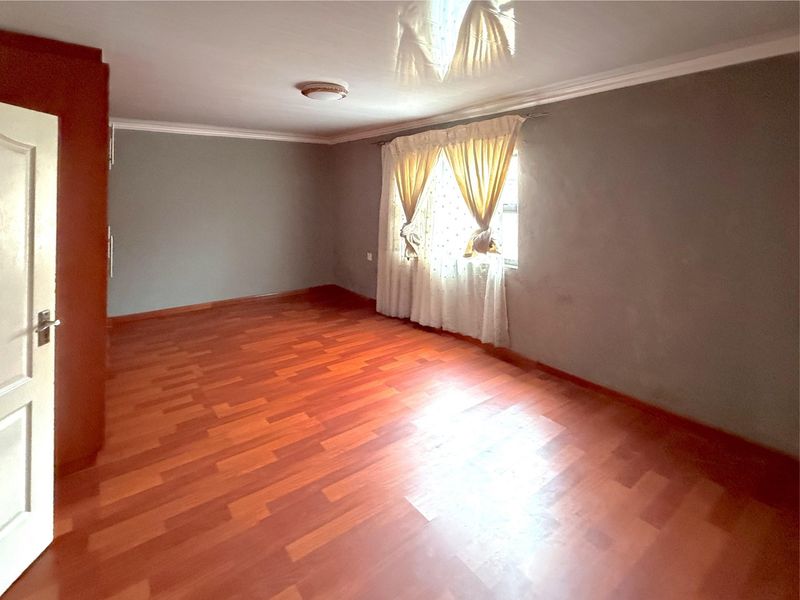 An empty bedroom featuring laminate flooring, a glossy ceiling, and a built-in cupboard, offering a blank canvas for personalization.