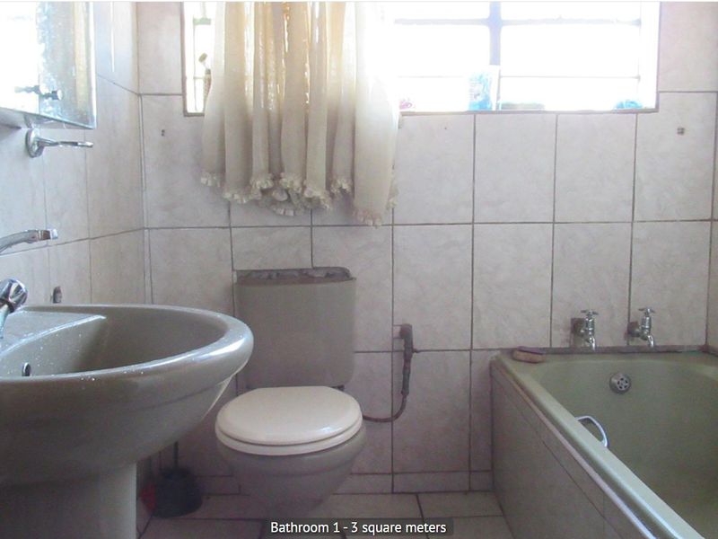 A compact bathroom featuring a pedestal basin, toilet, and bathtub with dated finishes, requiring modernization to improve functionality and aesthetic appeal.