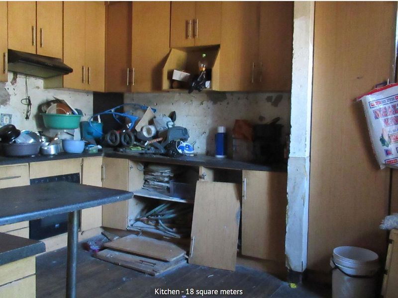 A dated kitchen featuring laminate cabinetry and built-in appliances, currently requiring significant renovation and repair to the wall finishes and cabinetry structure.