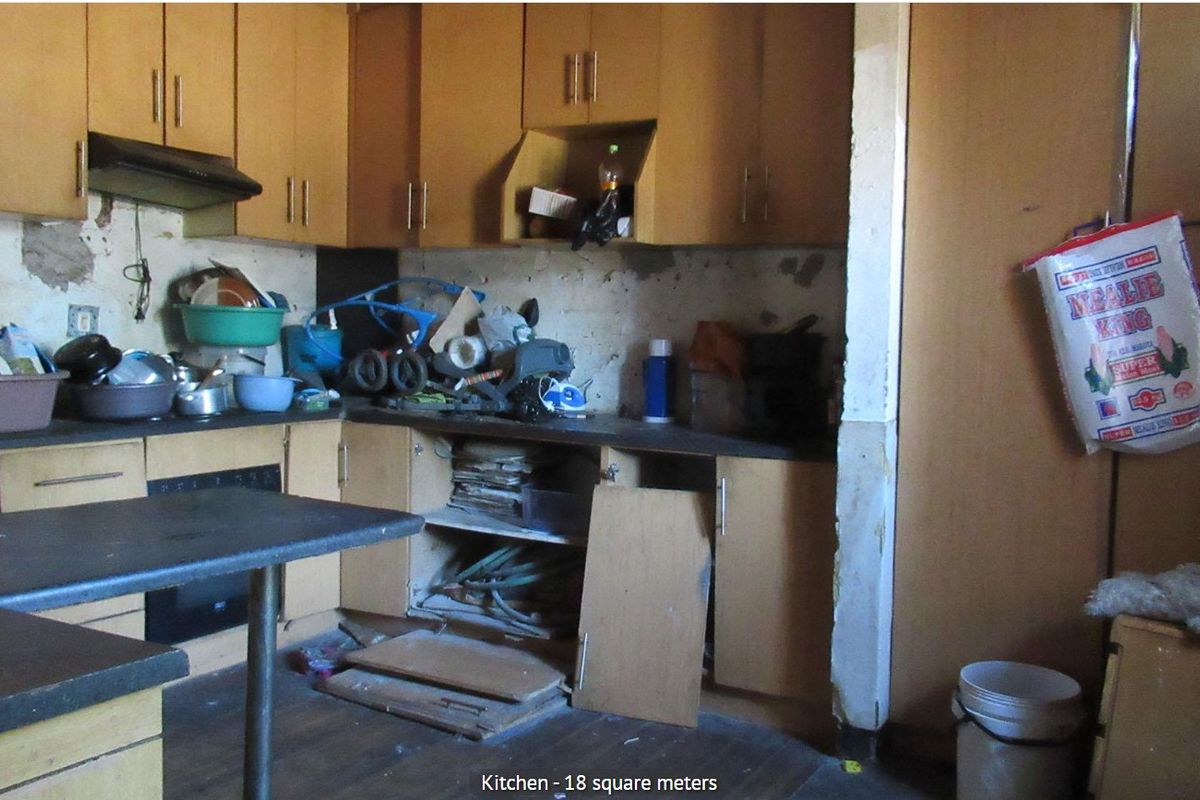 A dated kitchen featuring laminate cabinetry and built-in appliances, currently requiring significant renovation and repair to the wall finishes and cabinetry structure.