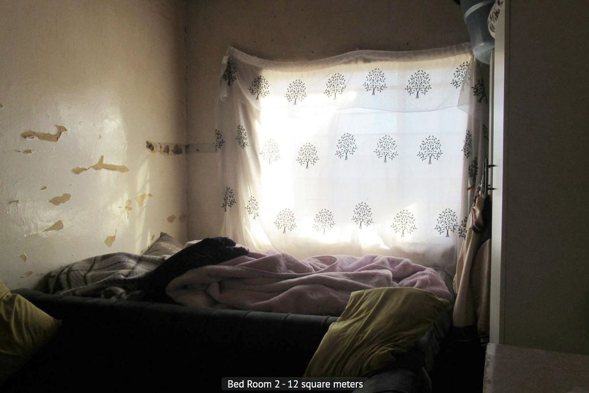 A bedroom featuring a built-in cupboard, requiring cosmetic attention to the walls due to peeling paint and plaster damage.