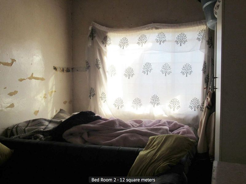 A bedroom featuring a built-in cupboard, requiring cosmetic attention to the walls due to peeling paint and plaster damage.
