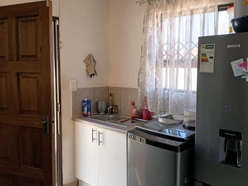 A functional laundry area featuring a stainless steel sink, built-in cabinetry, and tiled flooring, providing a practical space for household utility tasks.